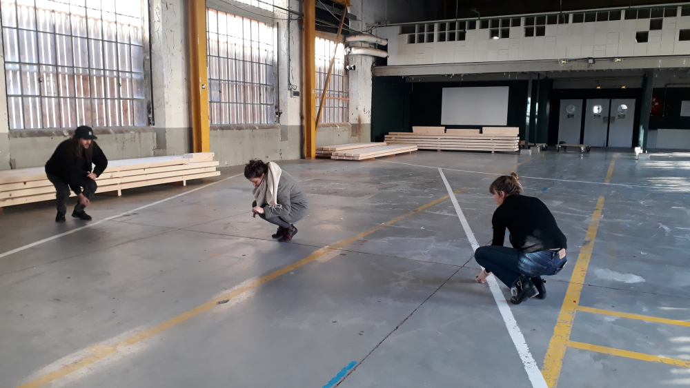 Trois personne scotchent des lignes droites sur le sol de l'atelier H.